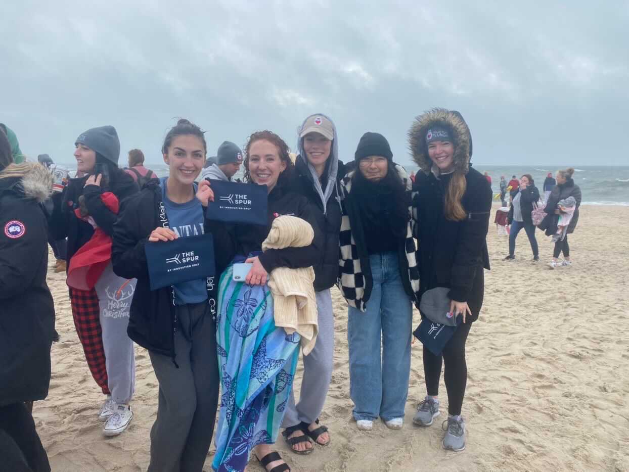 a group of women wearing warm clothing at the beach