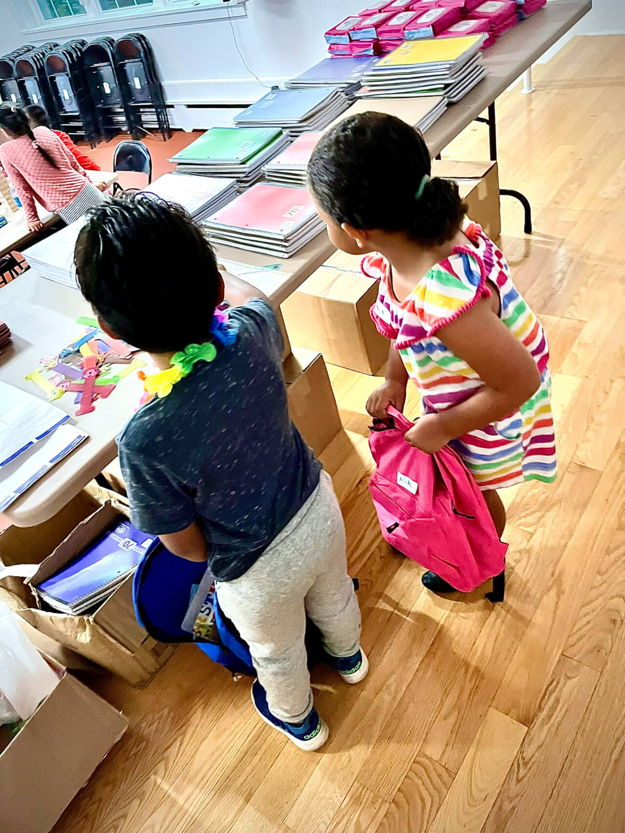 Two children picking up school things on table
